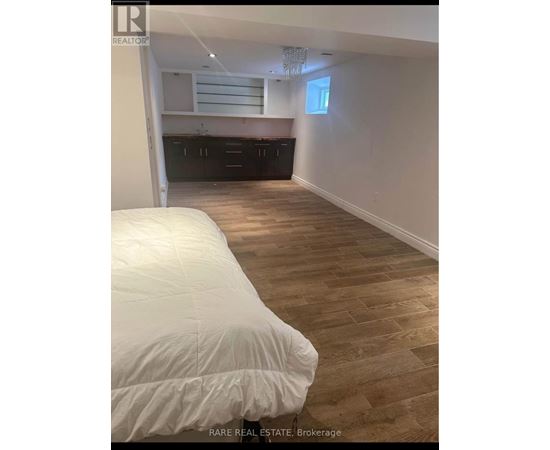 A bedroom with a bed and wooden flooring.
