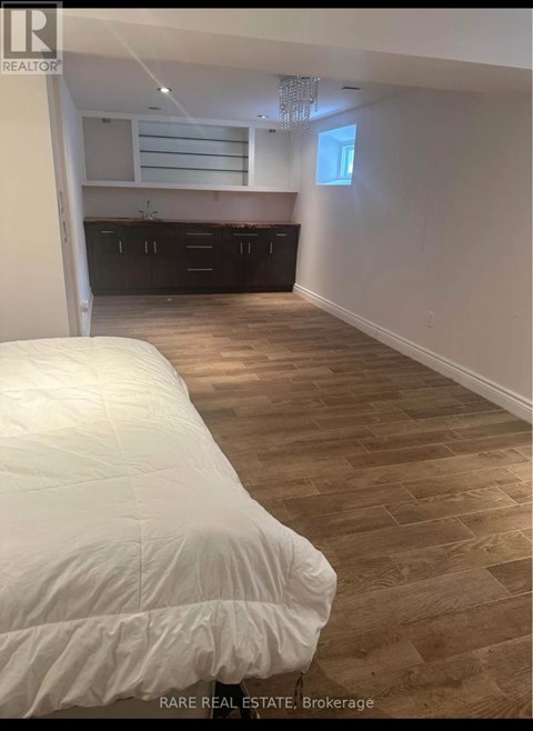 A bedroom with a bed and wooden flooring.
