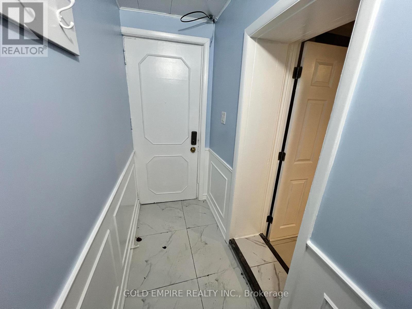A hallway with a white door and a white wall.