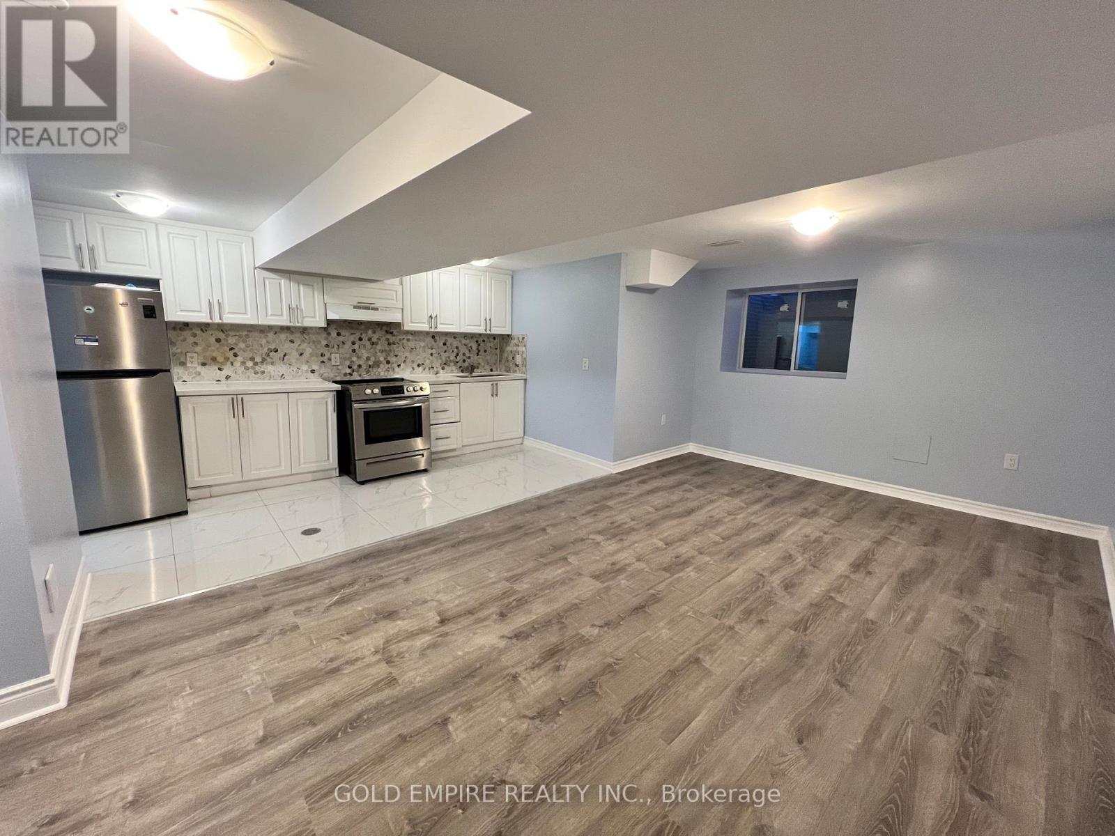 A spacious room with a stainless steel refrigerator and a built-in oven.