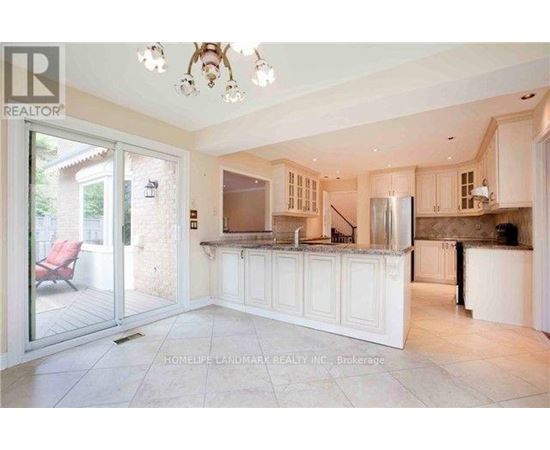A spacious kitchen with white cabinets and a refrigerator.