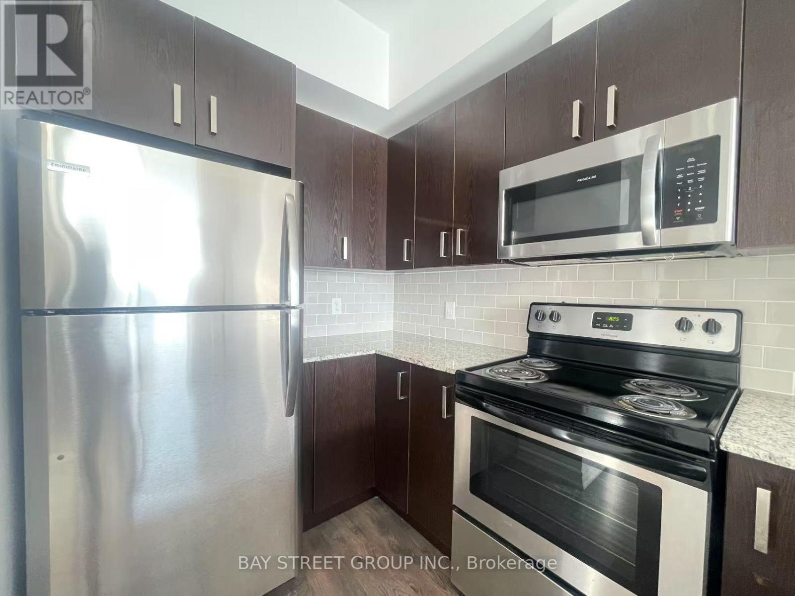 A kitchen with a stainless steel refrigerator, microwave, and oven.