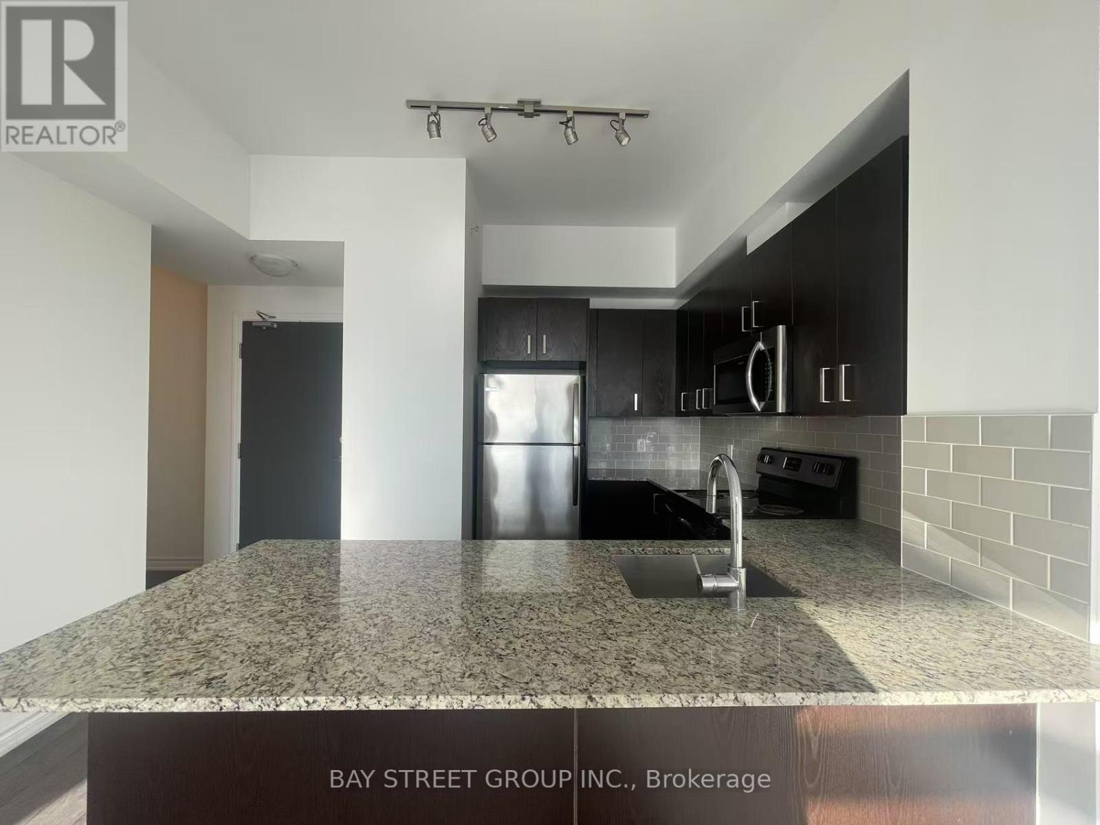 A kitchen with granite countertops and a stainless steel refrigerator.