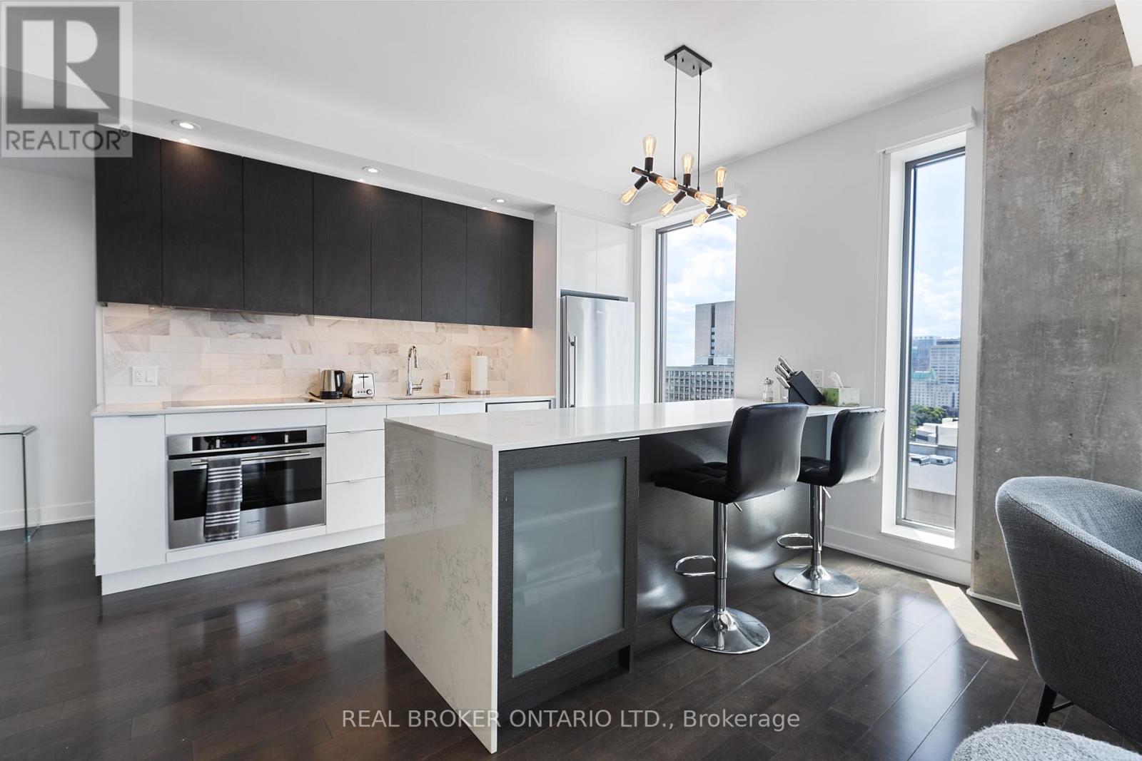 A modern kitchen with black cabinets and a marble backsplash.