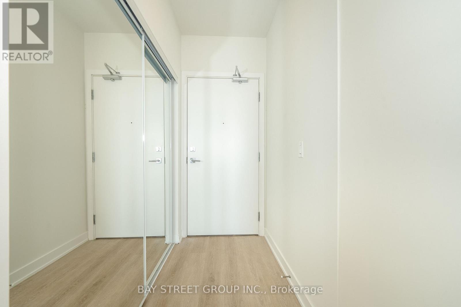 A white hallway with two doors and a brokerage sign.
