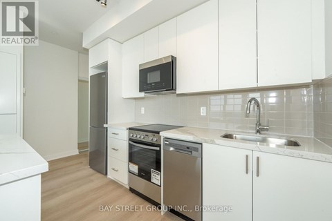 A kitchen with white cabinets and a black microwave above the stove.