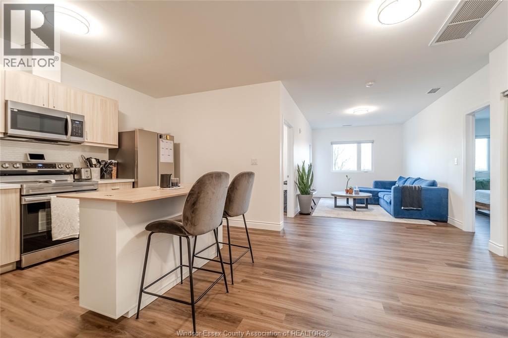 A well-lit kitchen with a bar stool and a dining table with chairs.