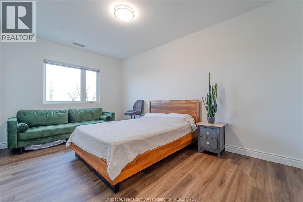 A bedroom with a bed, a green couch, and a plant.