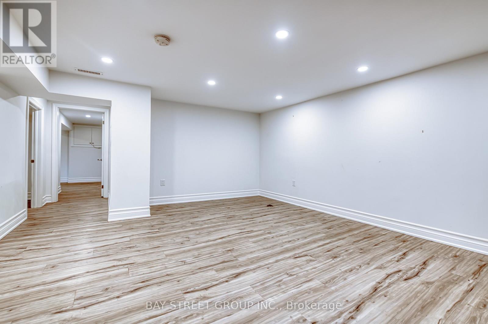 A spacious room with wooden flooring and white walls.