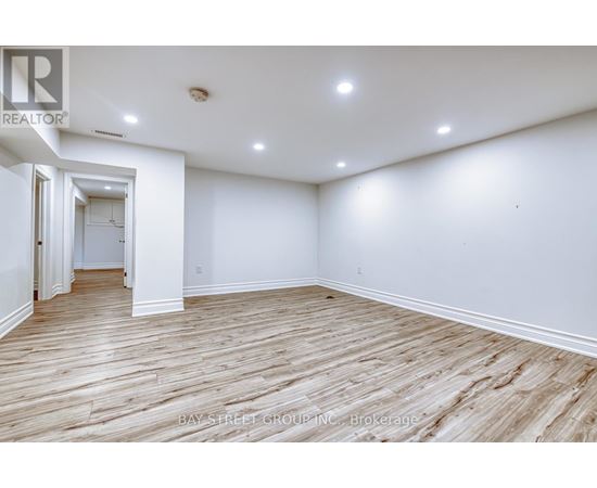 A spacious room with wooden flooring and white walls.