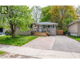 A house with a driveway and a tree in front.