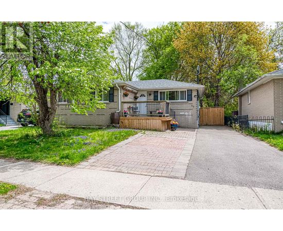 A house with a driveway and a tree in front.