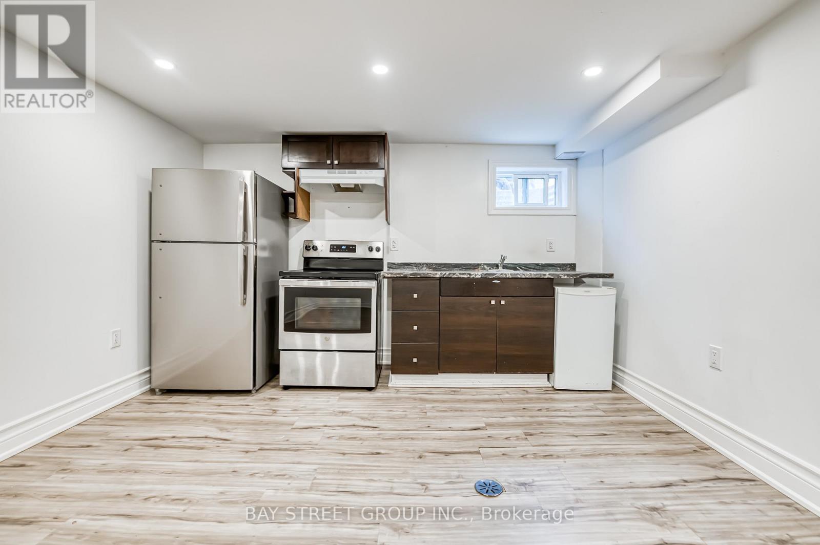 A kitchen with a refrigerator, oven, and dishwasher in a room with wooden flooring.