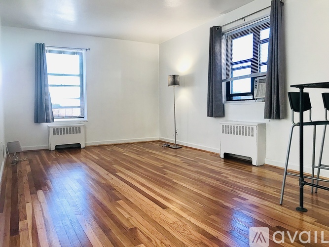 A room with wooden flooring and a window with curtains.