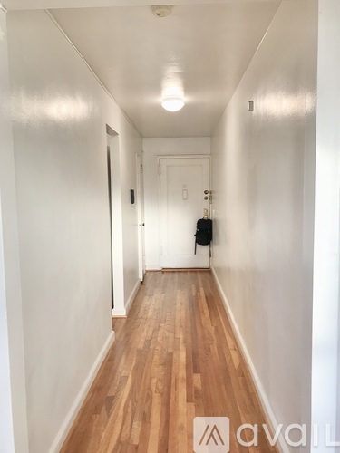 A hallway with wooden floors and white walls.