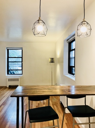 A dining room with a wooden table and two black chairs.