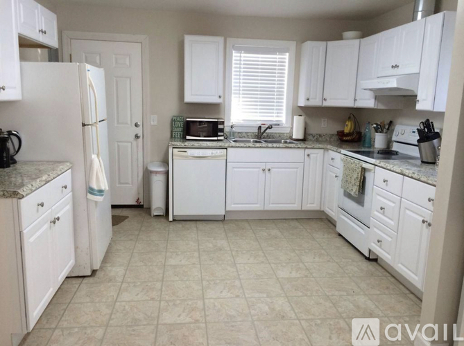 A kitchen with white cabinets and appliances.