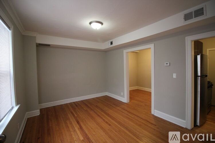 A room with wooden floors and white walls, with a window on the left side.