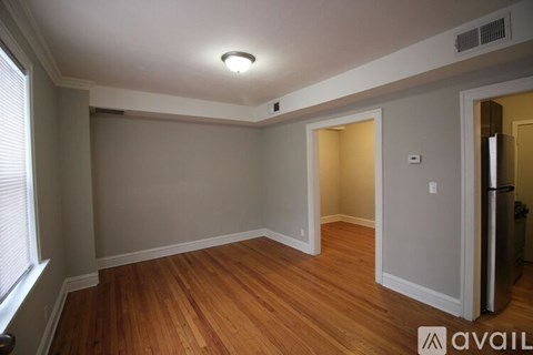 A room with wooden floors and white walls, with a window on the left side.