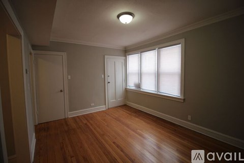 A room with wooden floors and a window with blinds.