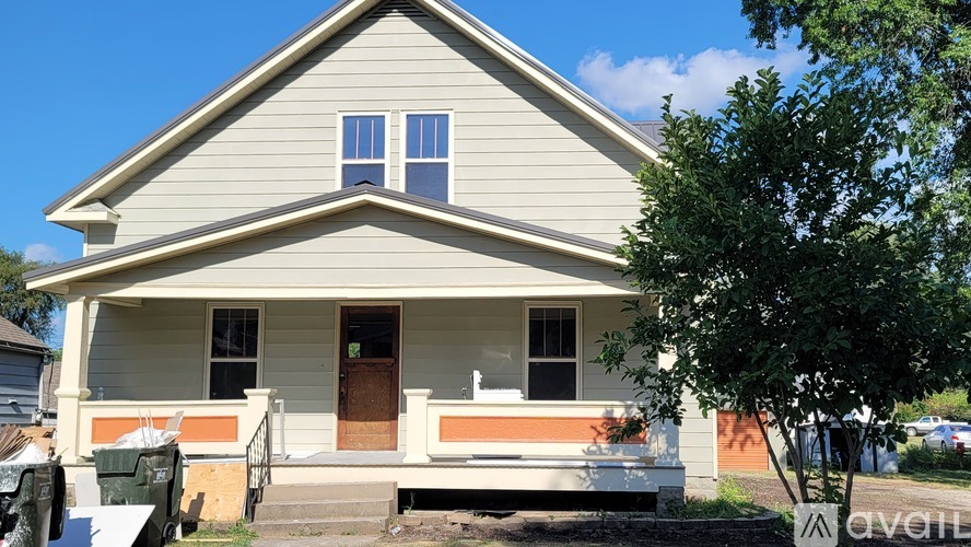 A two-story house with a front porch and a brown door.