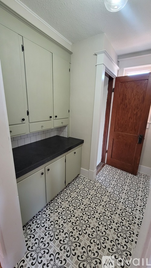 A kitchen with white cabinets and a black counter top.