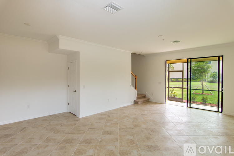 A spacious empty room with tiled flooring and a view of a backyard through a glass door.
