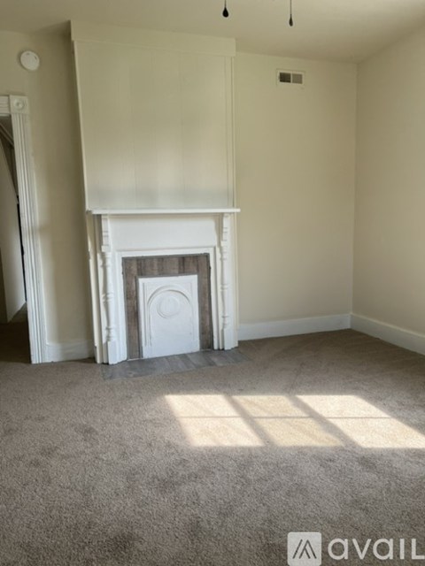 A room with a fireplace and carpeted floor.