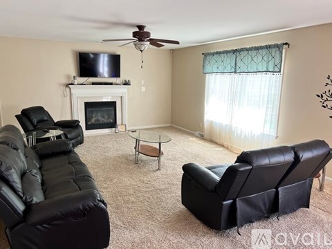 A living room with a black leather couch and a television.