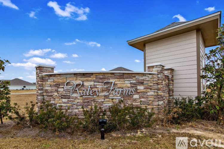 A stone sign that says "Raley Farms" stands in front of a house.