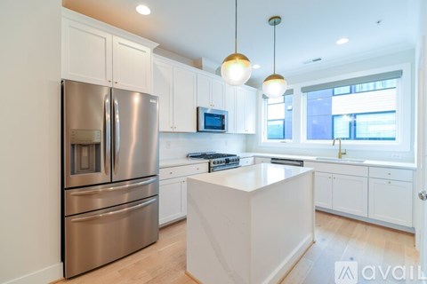 A modern kitchen with a stainless steel refrigerator and a central island.