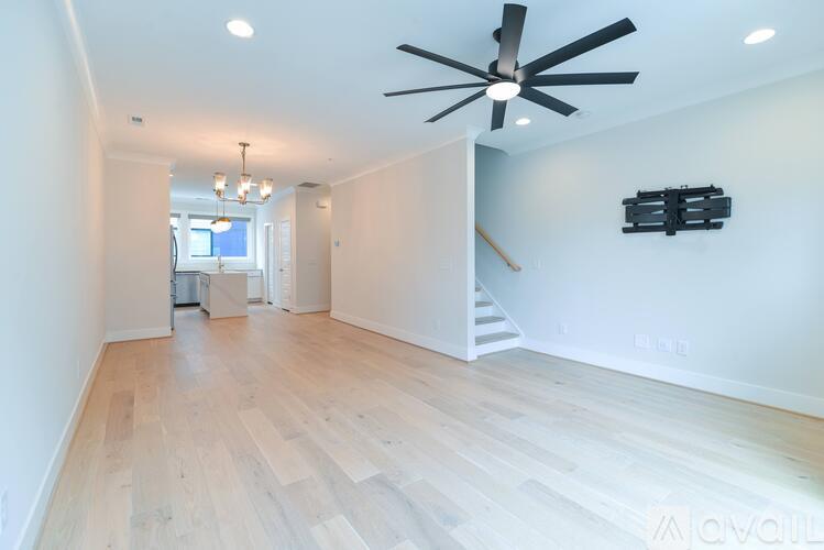 A spacious room with wooden flooring and a ceiling fan.