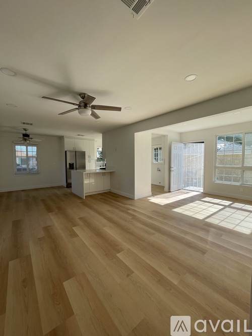 A spacious room with wooden flooring and a ceiling fan.