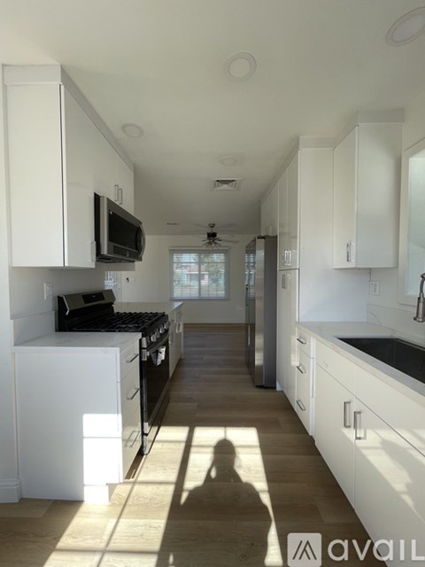 A kitchen with white cabinets and black appliances.