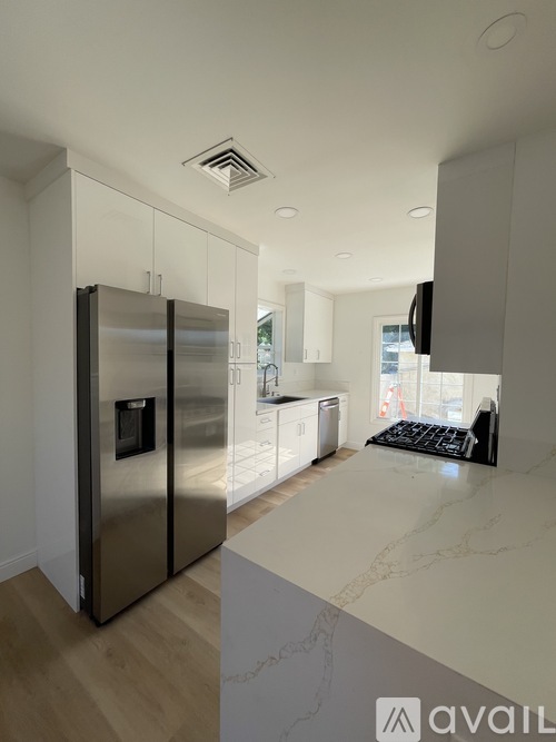 A modern kitchen with a stainless steel refrigerator and a marble countertop.