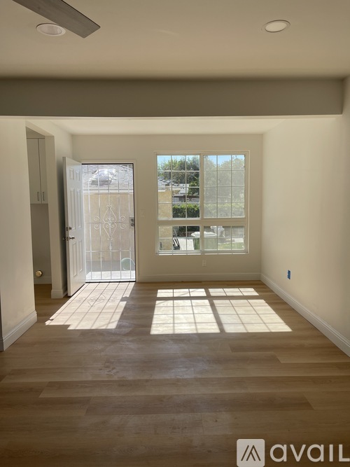 A room with wooden flooring and a large window with a view of a building outside.