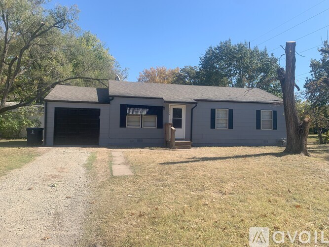 A two-story house with a garage and a tree in front.