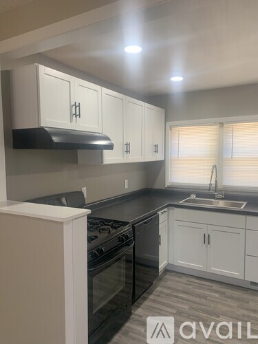 A kitchen with white cabinets and black appliances.