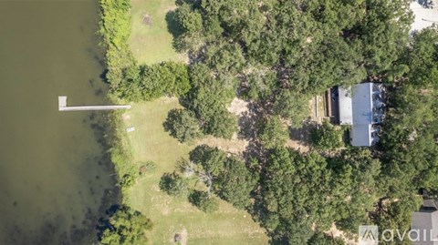 An aerial view of a house surrounded by trees and a body of water.
