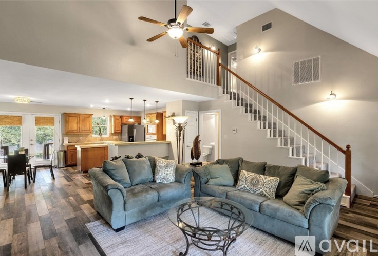 A living room with a grey couch and a fan on the ceiling.