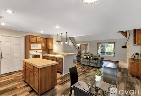 A kitchen with a wooden island and a dining table with chairs.