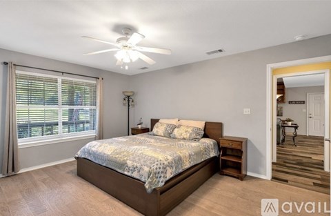 A bedroom with a bed, nightstand, and window with blinds.