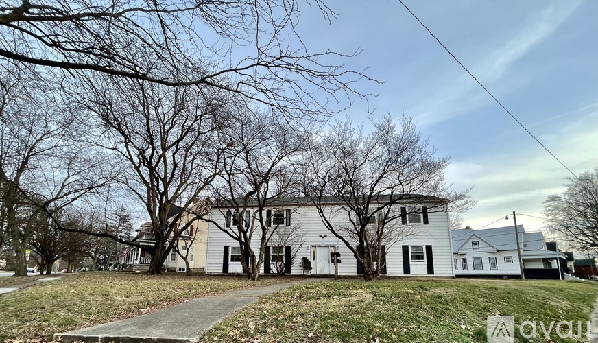 A white house with a grey roof is surrounded by bare trees.