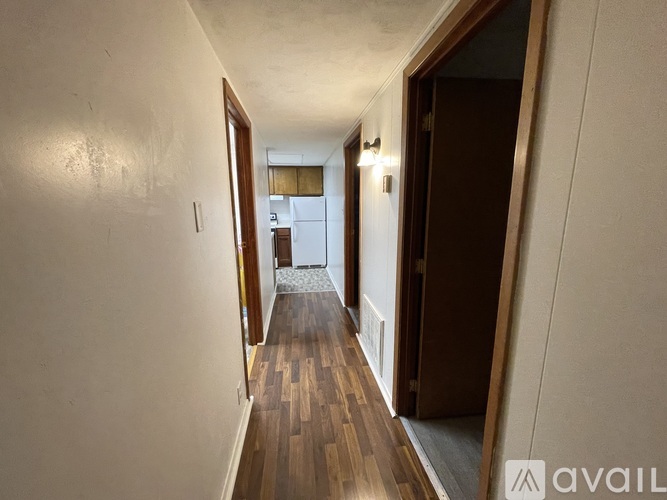 A long hallway with a wooden floor and white walls.