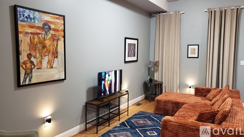 A living room with a television, a sofa, and a painting on the wall.