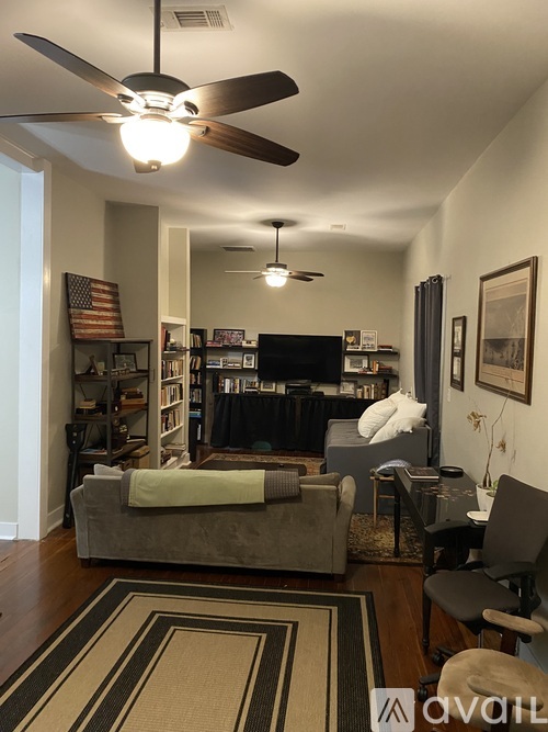 A living room with a grey couch and a rug.
