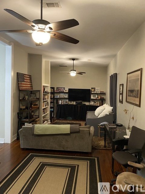 A living room with a grey couch and a rug.