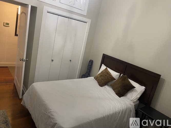 A bedroom with a bed, pillows, and a cabinet.
