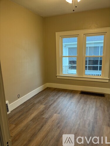 A room with wooden floors and a window with a view of a building outside.
