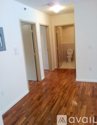 A room with wood flooring and two doors leading to another room.